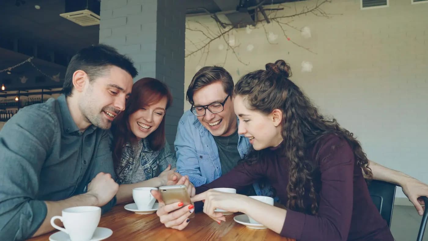 Vrienden kijken lachend samen op een telefoon