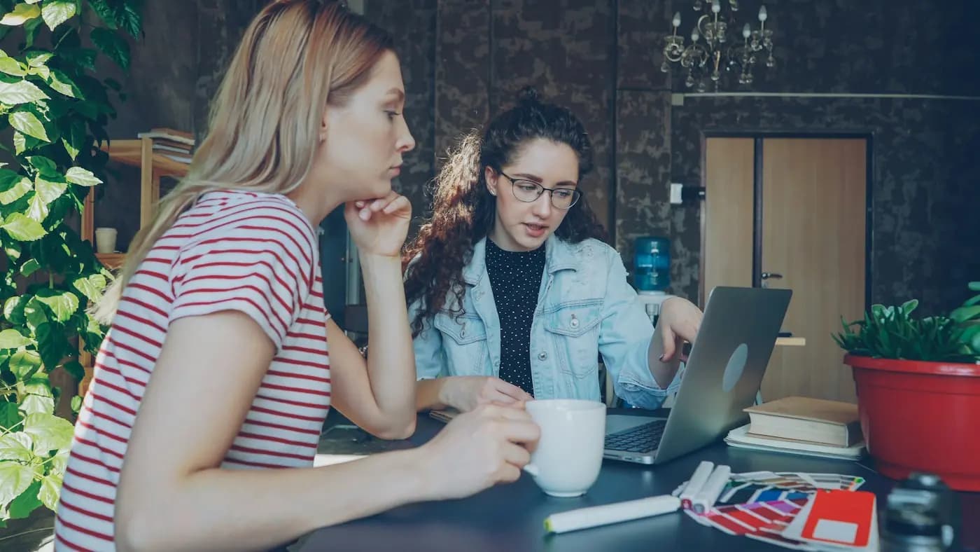 Twee vriendinnen bespreken plannen achter een laptop
