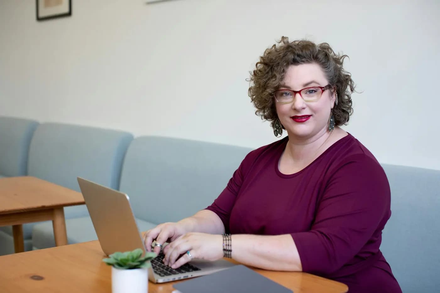 Een vrouw werkt glimlachend op haar laptop