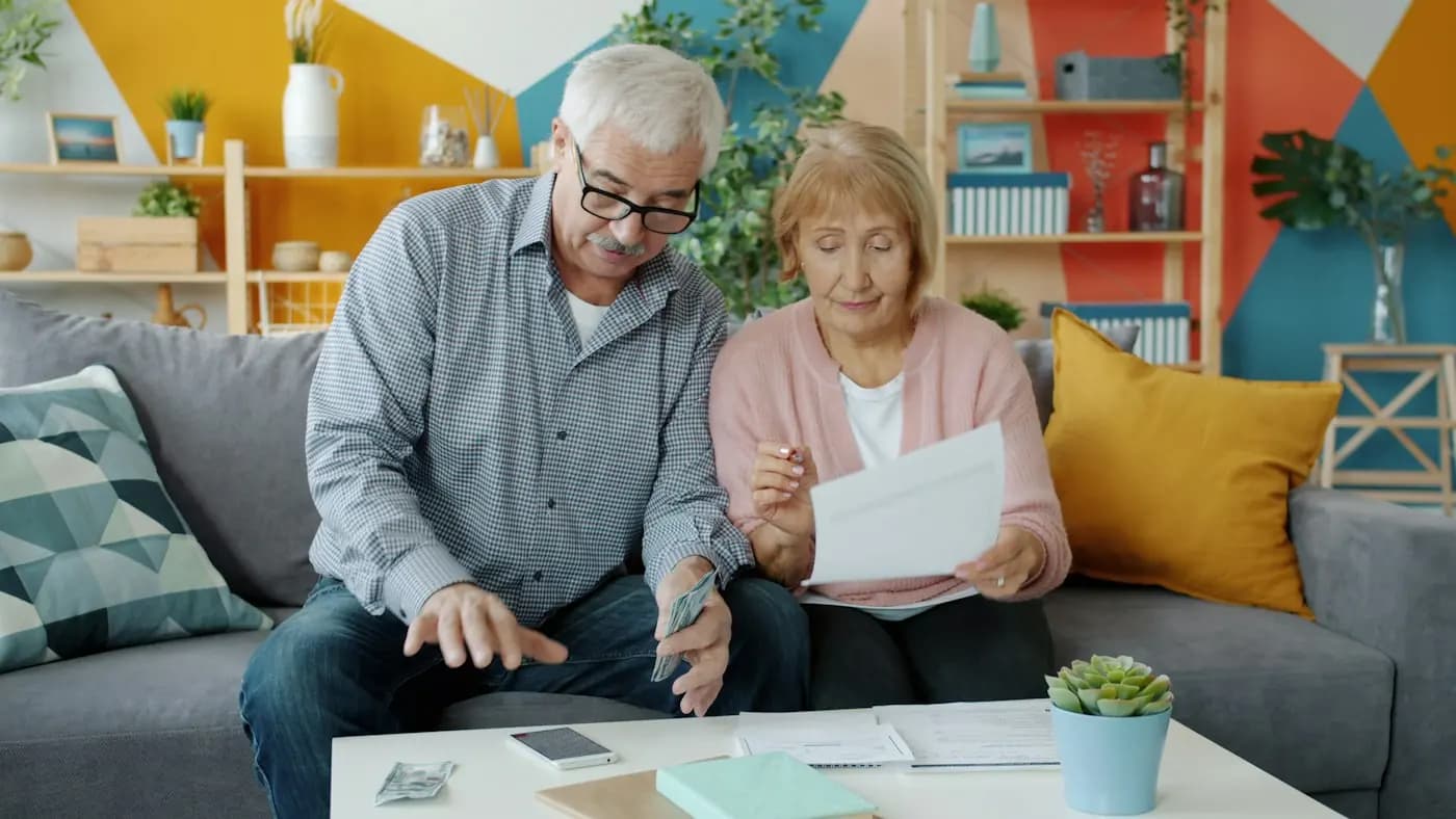 Een ouder stel rekent samen op de bank de kosten door